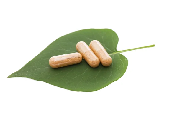 Таблетки на зеленом листе соляные на белом — стоковое фото