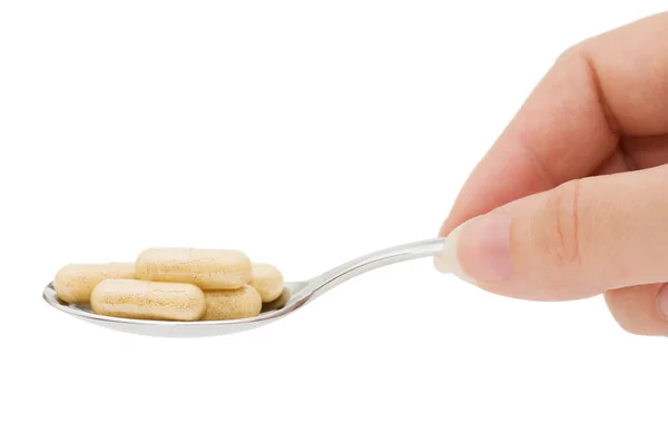 Pillole in un cucchiaio isolato su sfondo bianco — Foto Stock