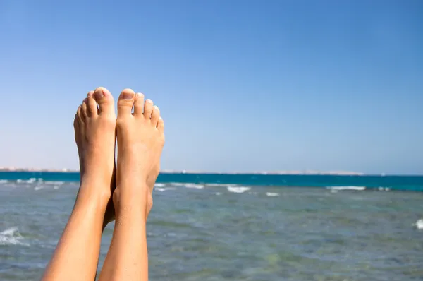 Ženské nohy proti moři — Stock fotografie