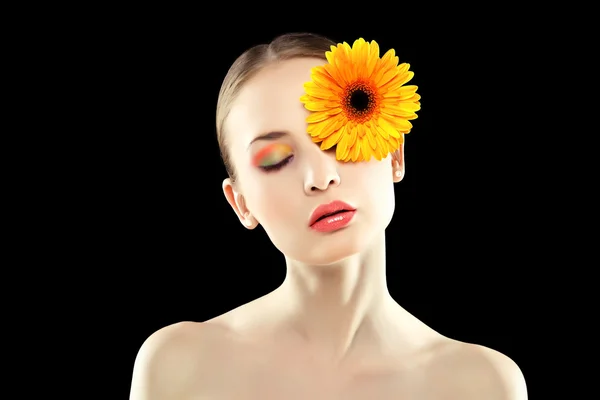 Kvinna med en orange blomma. Stockbild