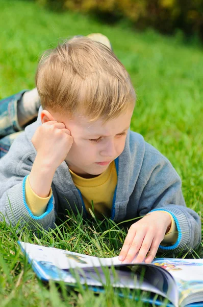 Kleiner Junge liest draußen ein Buch — Stockfoto