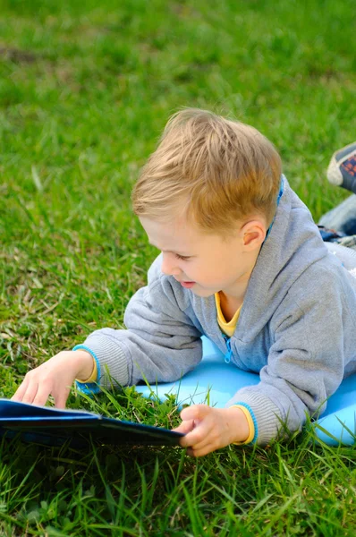 Little boy is reading a book outdoor — Stock Photo, Image