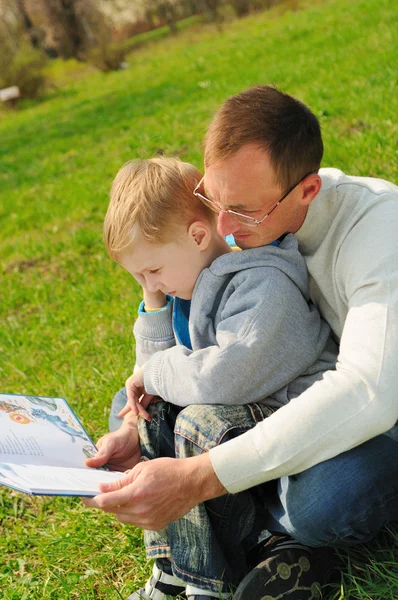 Little boy and his father are reading a book outdoor — Stock Photo, Image