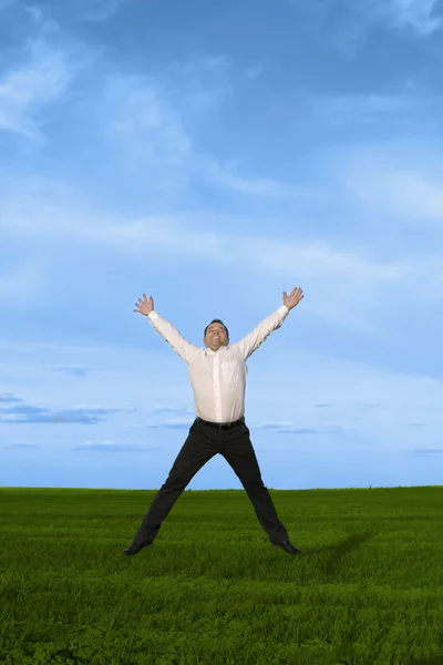 Бизнесмен прыгает по зеленой траве — стоковое фото