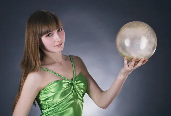 Жінка в зеленій сукні з золотою сферою — стокове фото