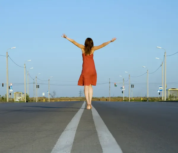 Girl in red dress walk barefoot on empty road — Stock Photo, Image