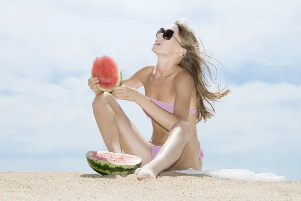 Женщина позирует на пляже и ест арбуз — стоковое фото