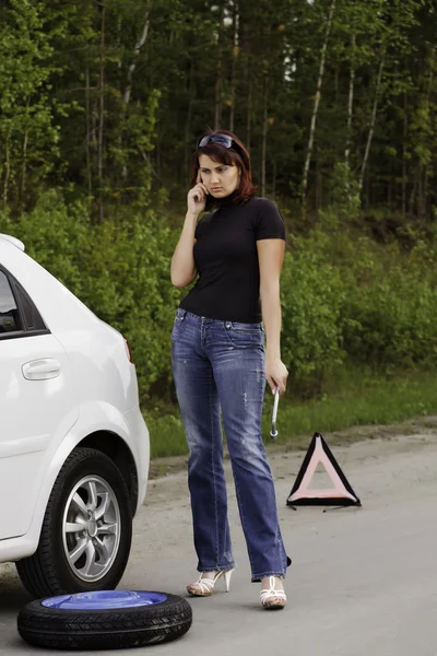 Frau ruft einen Dienst an, der neben einem weißen Auto steht — Stockfoto