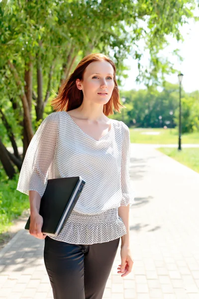 Vrouw met laptop onder de hand wandelen — Stockfoto