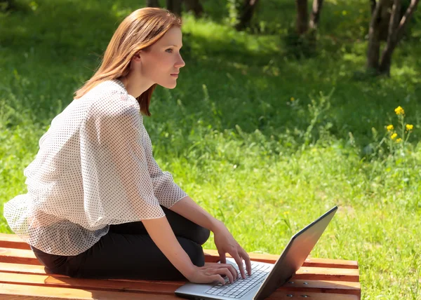 Красивая молодая женщина с ноутбуком в парке — стоковое фото