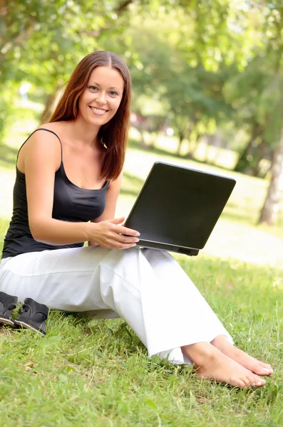 Mujer joven y bonita con un portátil en el parque —  Fotos de Stock