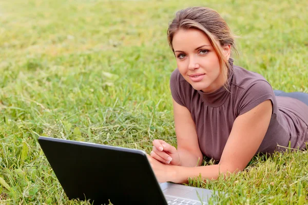 Ganska ung kvinna med en laptop på park — Stockfoto