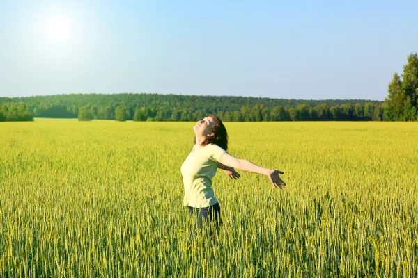 Mujer con los brazos abiertos en el campo de cereales verde . — Foto de Stock