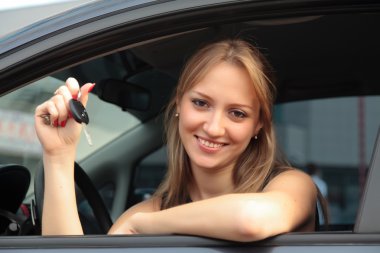 The happy woman showing the key of her new car clipart