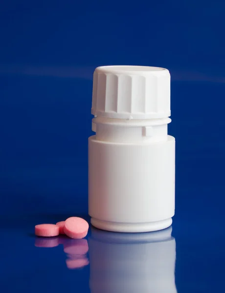 Botol putih dengan tablet merah muda di biru — Stok Foto