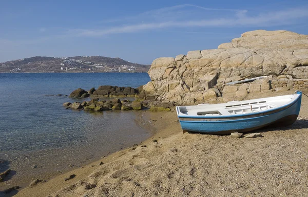 Одинокая лодка на пляже у скал — стоковое фото