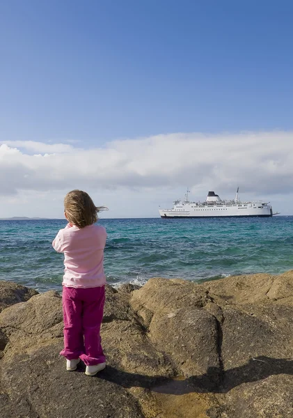 Маленький ребенок на берегу наблюдает за кораблем — стоковое фото