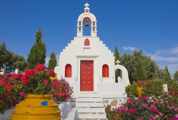 Die weiße griechische Kirche in einem Garten — Stockfoto