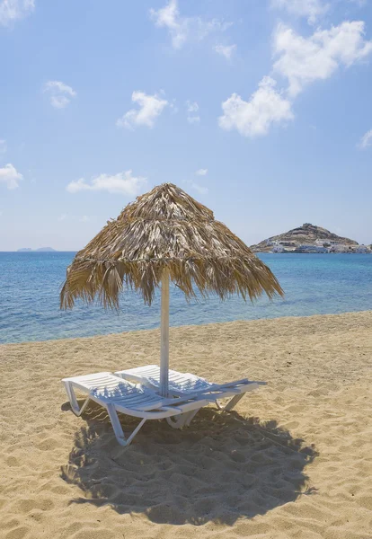 Paraply av vass och solstolar på stranden — Stockfoto
