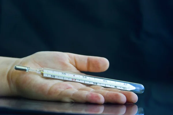 stock image The sick hand of the child holds a thermometer