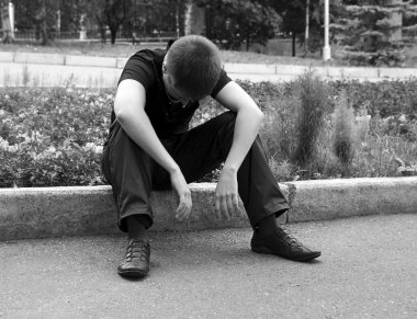 Upset boy, sits on a bed in park clipart