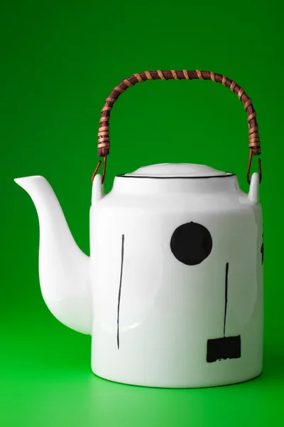 Weiße Teekanne mit Holzgriff auf grünem Hintergrund — Stockfoto