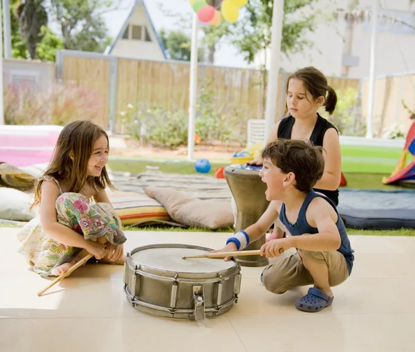 Троє дітей розважаються з барабанами — стокове фото