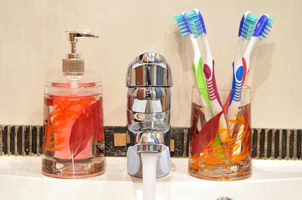 Jabón líquido, grifo, cuatro cepillos de dientes —  Fotos de Stock