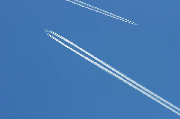 Летит самолет по голубому небу оставляя белый! — стоковое фото