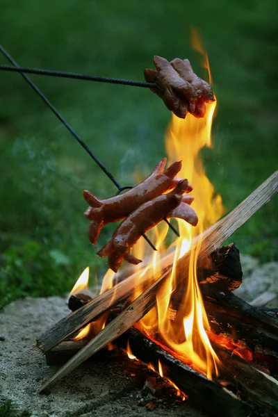 Roasting sausages on campfire in the garden — Stock Photo, Image