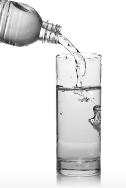 Water pouring into glass from bottle — Stock Photo, Image