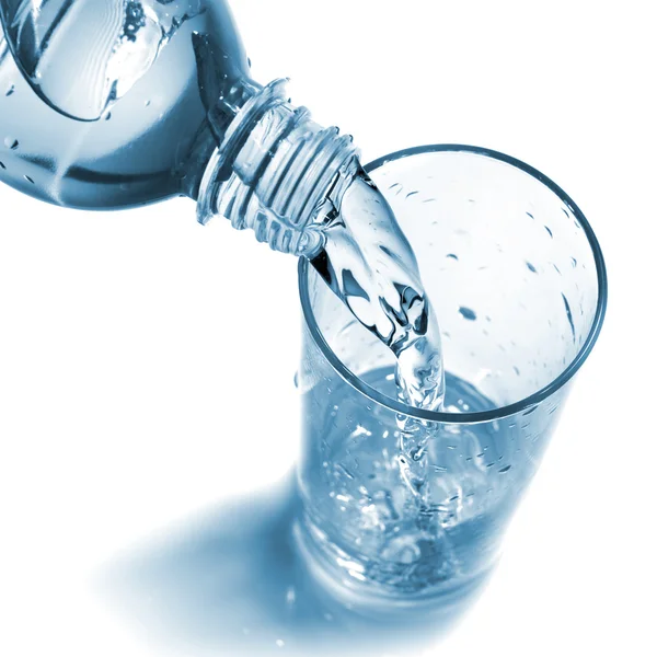 Вода из бутылки льется в стекло — стоковое фото