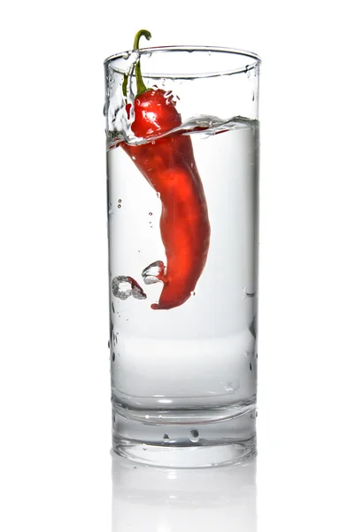 Красный перец упал в стакан с водой — стоковое фото
