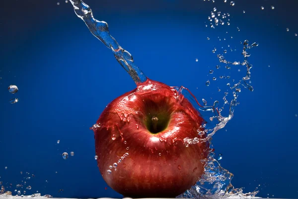 Roter Apfel mit Wasserspritzer auf blauem — Stockfoto
