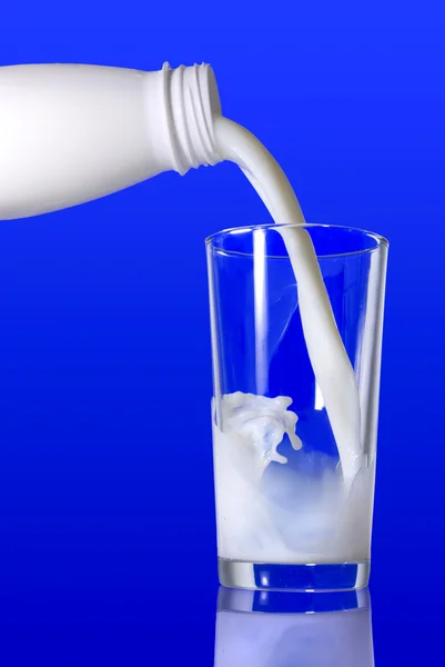 Latte versato dalla bottiglia nel vetro — Foto Stock