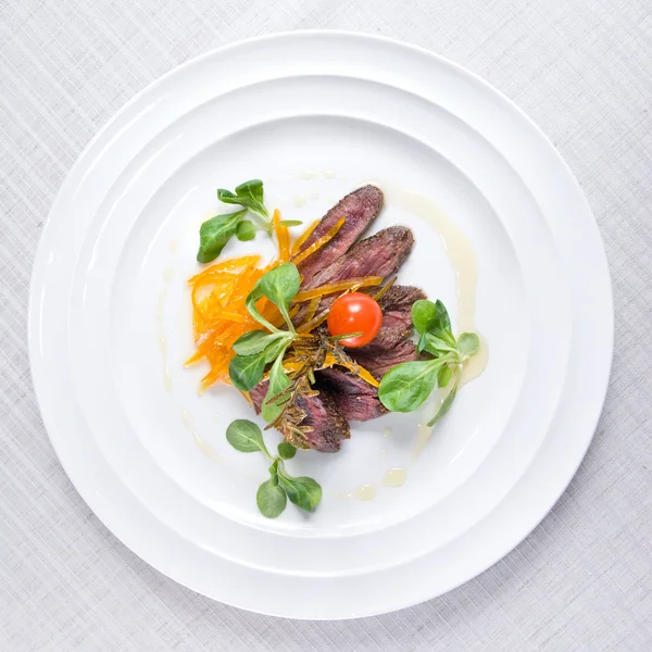 Жареное мясо с овощами на тарелке — стоковое фото