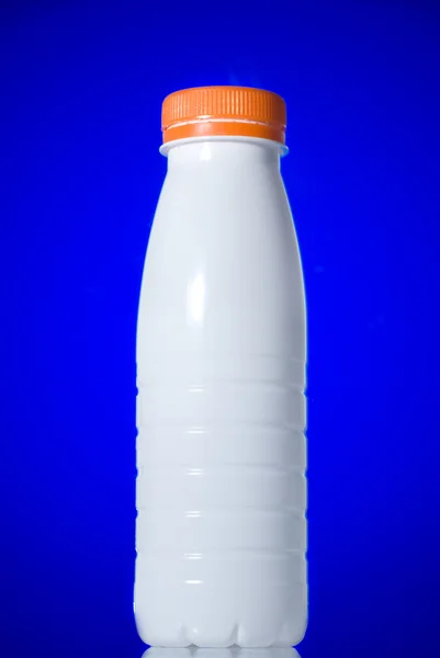 White milk bottle isolated on blue — Stock Photo, Image