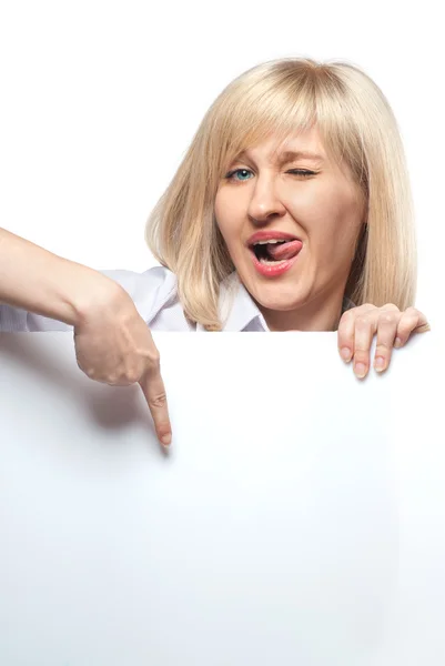 Atractiva mujer divertida sosteniendo papel blanco vacío y señalándolo — Foto de Stock