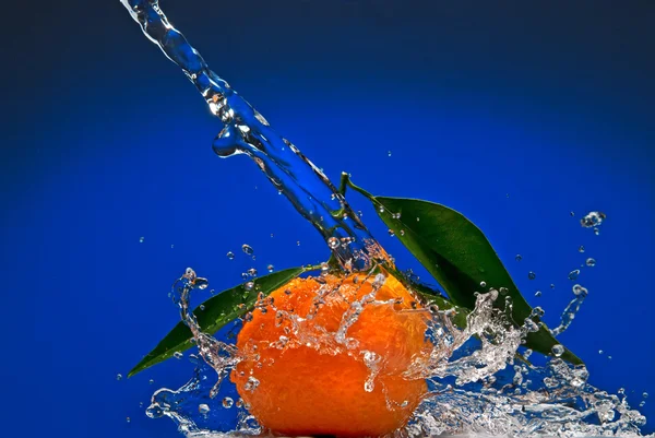 Mandarine mit grünen Blättern und Wasserspritzer — Stockfoto
