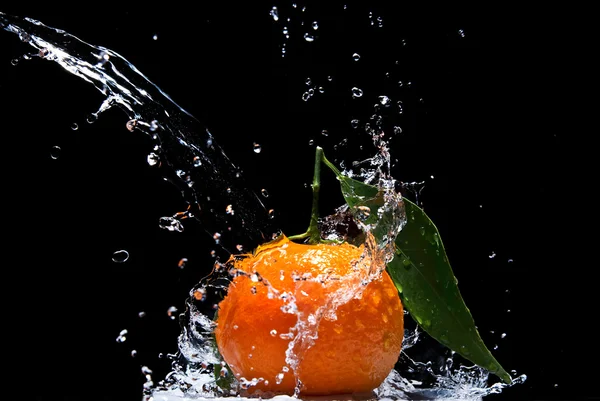 Mandarinky s zelenými listy a stříkající vodě — Stock fotografie