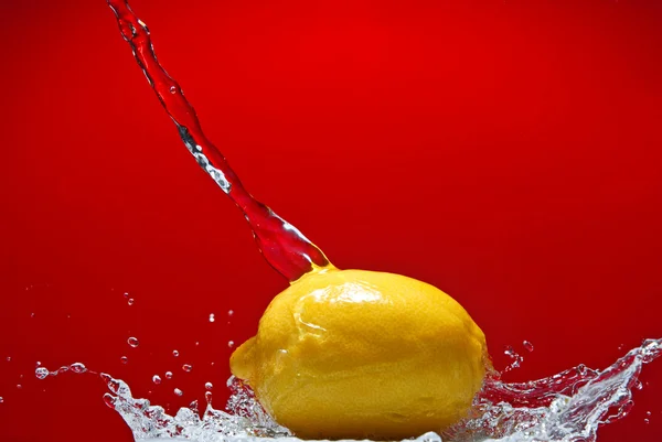Fresh lemon and water splash on red — Stock Photo, Image