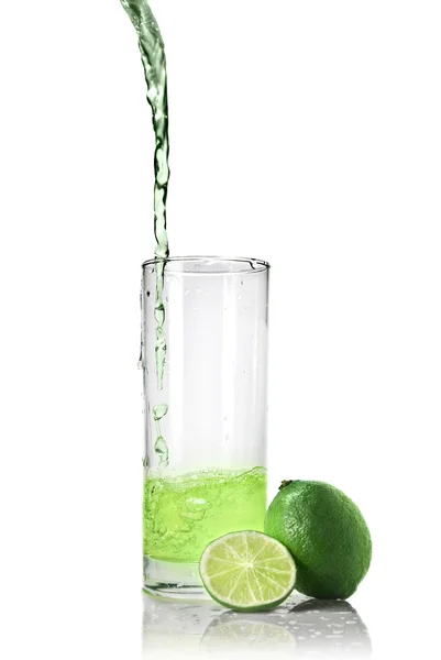 Green juice with lime pouring into glass — Stock fotografie