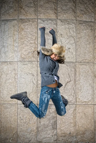 Junge Frau springt mit Pelzmütze gegen die Wand — Stockfoto