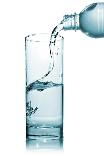 Voda proudí do skla z láhve — Stock fotografie