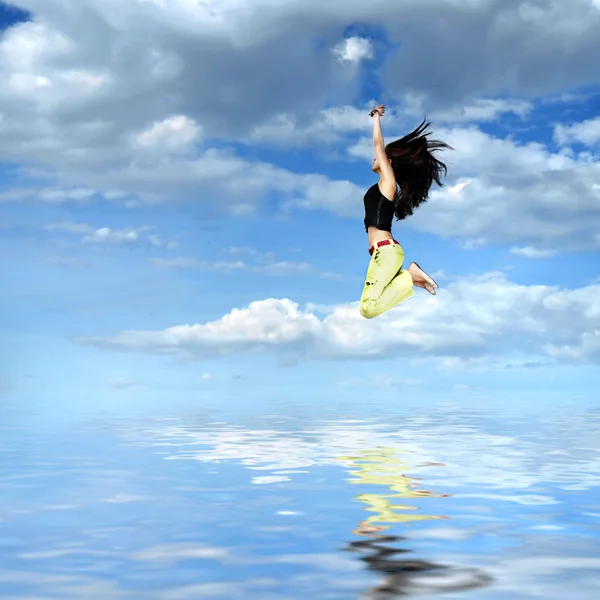 跳跃的反对蓝蓝的天空和太阳的女孩 — 图库照片