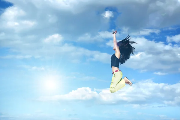 Girl jumping against blue sky and sun — Stock Photo, Image