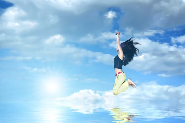 Flickan hoppar mot blå himmel och sol — Stockfoto