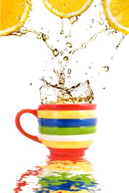 Lemon juice and splash of tea in color cup with reflection clipart