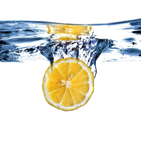 Свежий лимон капал в воду с пузырьками — стоковое фото