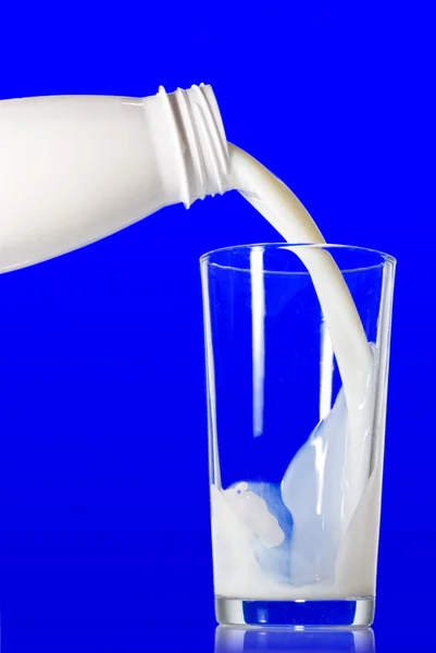 Mjölk hälla från flaska i glas — Stockfoto